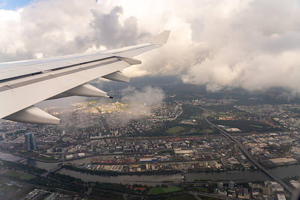 istock Airplane wing over city with river and clouds. 2244074852