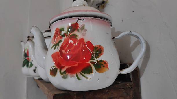 istock Vintage enamel teapots sit on a shelf, adorned with floral patterns 2244076334