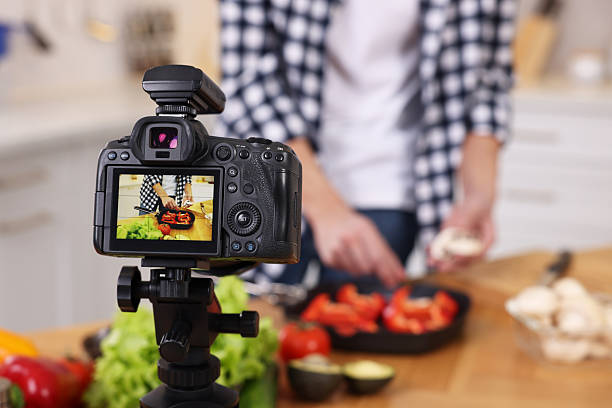 istock Food blogger cooking while recording video in kitchen, focus on camera 2244076426