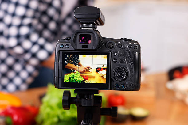 istock Food blogger cooking while recording video in kitchen, focus on camera 2244076436