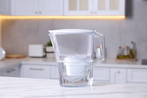 istock Water filter jug on white marble table in kitchen, closeup 2244076448