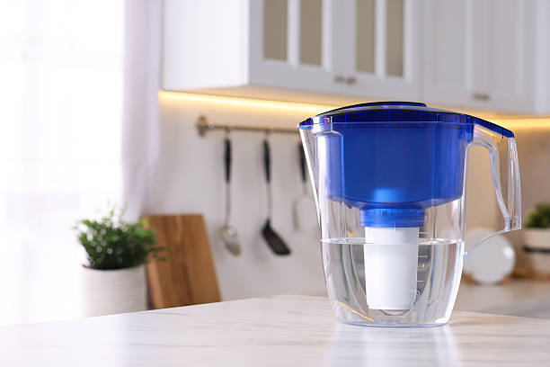 istock Water filter jug on white marble table in kitchen, closeup. Space for text 2244076450
