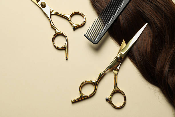 istock Professional scissors and comb with brown hair strand on beige background, flat lay 2244077553