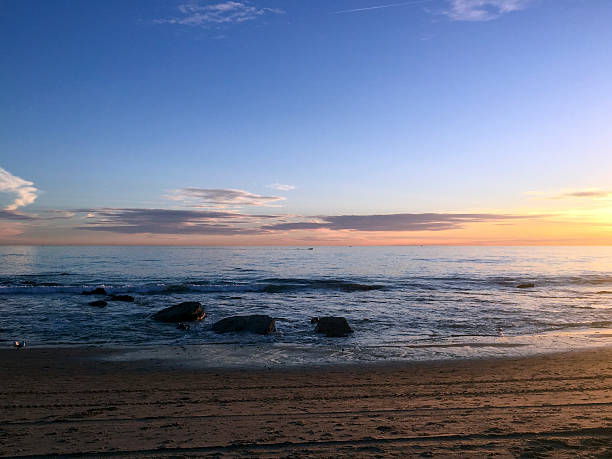 istock Beautiful sunset over the calm ocean with waves and rocks 2244078225