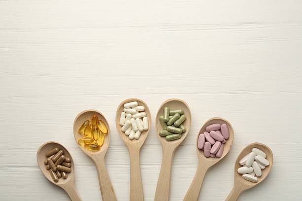 istock Different vitamin capsules in spoons on white wooden table, flat lay. Space for text 2244081757