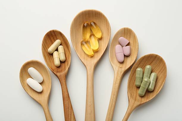 istock Vitamin capsules in wooden spoons on white background, flat lay 2244081774