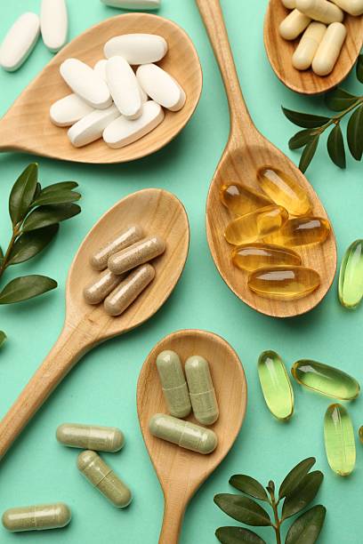 istock Different vitamin capsules in spoons and leaves on turquoise background, flat lay 2244081813