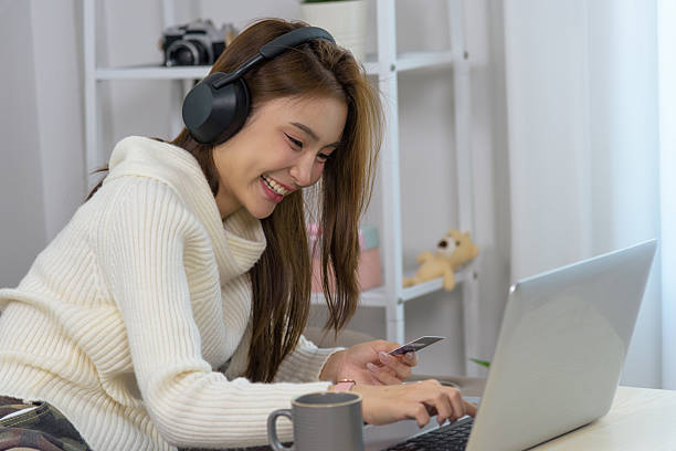 istock Young woman at home, happy people enjoy online shopping activity, using laptop computer with credit card, buying goods, wearing headphones, smiling, modern leisure 2244082078