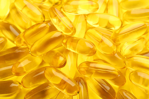 istock Many vitamin capsules on yellow background, closeup 2244083377