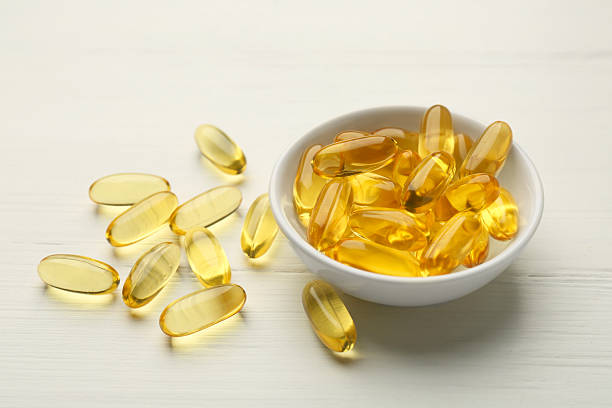 istock Vitamin capsules in bowl on white wooden table 2244083435