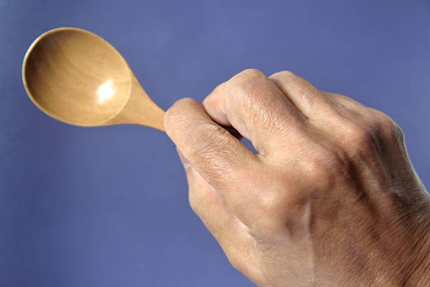 Young Asian woman wearing red apron and holding wooden ladle ready to cooking isolated on white background
