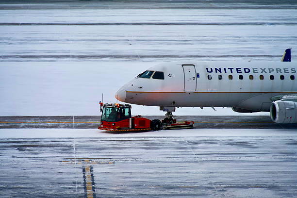 Denver, Colorado, USA - February 15, 2025: A United Express Embraer E175LR passenger aircraft at Denver International Airport during a winter snowstorm.