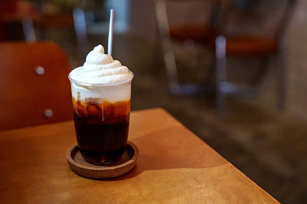 Iced coffee with whipped cream on wooden table in cafe