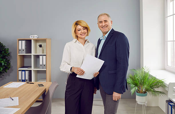 istock Two smiling business people with paper documents standing in office 2244096246