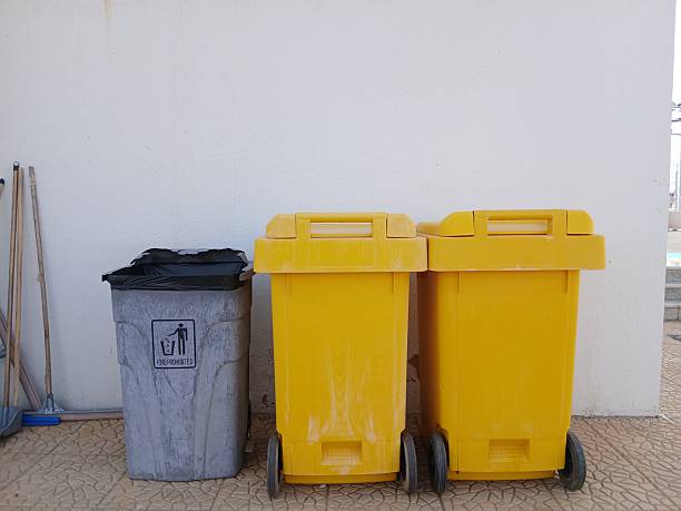 istock Two yellow trash cans, a gray trash can, mops and brooms, and a yellow wall 2244097969