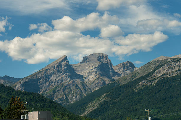Majestic rocky mountains against a vibrant blue sky dotted with white clouds. Fernie, BC