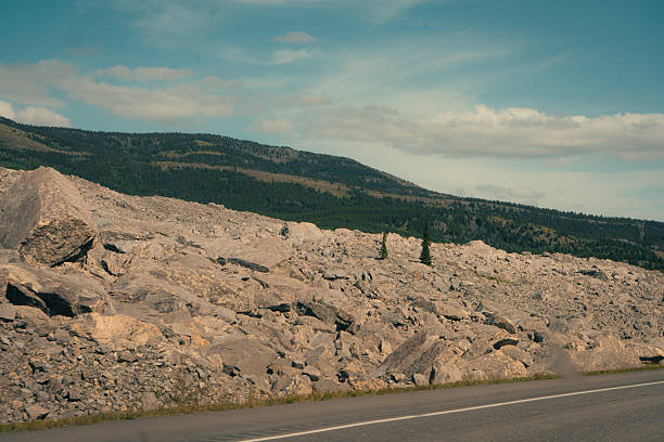 Rocky mountainside with scattered trees under a partially cloudy sky scene. Frank Slide, AB