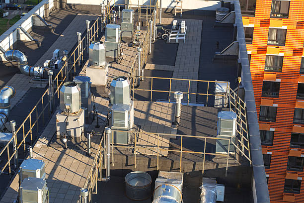 istock Modern building rooftop with ventilation and air conditioning systems, industrial metal pipes, and safety railings, symbolizing urban infrastructure, technology, energy efficiency, and engineering solutions 2244098914