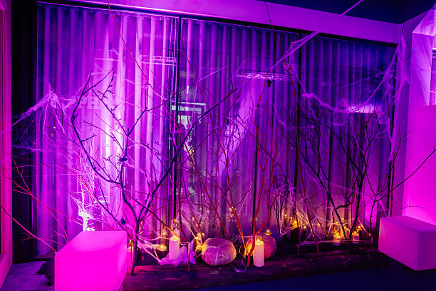Spooky Halloween-themed interior with purple lighting, bare branches, and cobwebs creating an eerie atmosphere, perfect for festive decorations and seasonal celebrations