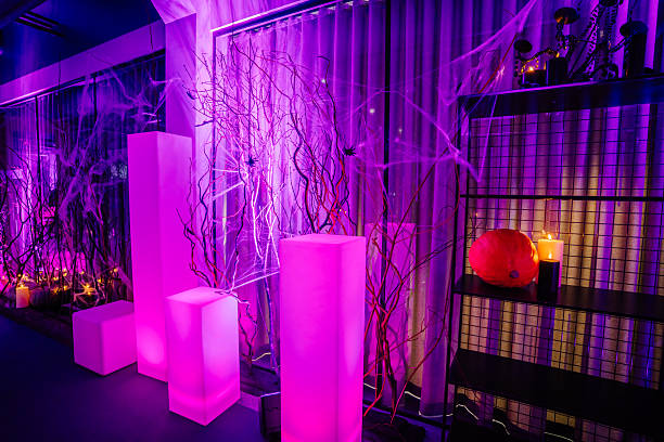 istock Vibrant Halloween-themed interior featuring illuminated purple decor, spooky branches, glowing candles, and a carved pumpkin, creating an enchanting atmosphere for festive celebrations 2244099224