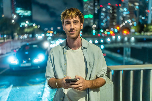 istock Young man smiling and texting on phone at night 2244100473