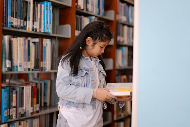 istock A young girl is reading the book at the library. 2244102505