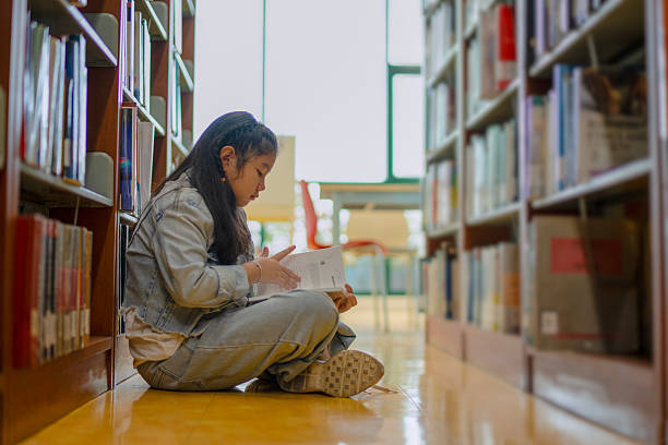 istock A young girl is reading the book at the library. 2244102521