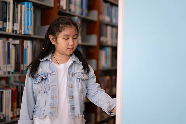 A young girl is reading the book at the library. Knowledge and education.