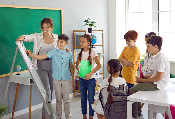 istock Elementary school students use whiteboard together with the teacher during lesson. 2244102605