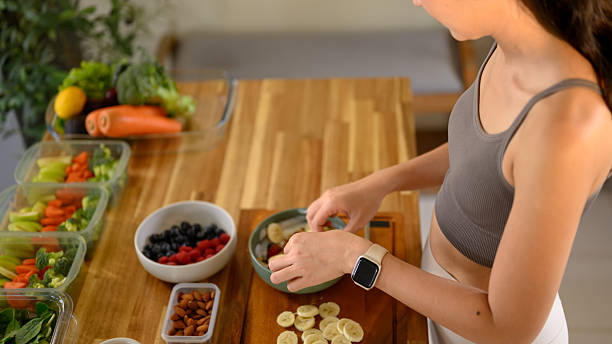 Female hands arranging fruits into a yogurt bowl, healthy breakfast concept with clean eating and wellness.