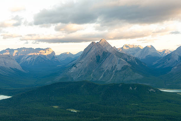 Overlooking a valley of trees with mountains and clouds. Tent Ridge, Kananaskis, AB