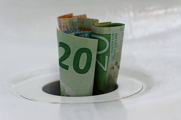 istock New Zealand dollars down a white plug hole 2244105925