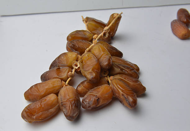 Cluster of Deglet Nour dates displayed on white surface