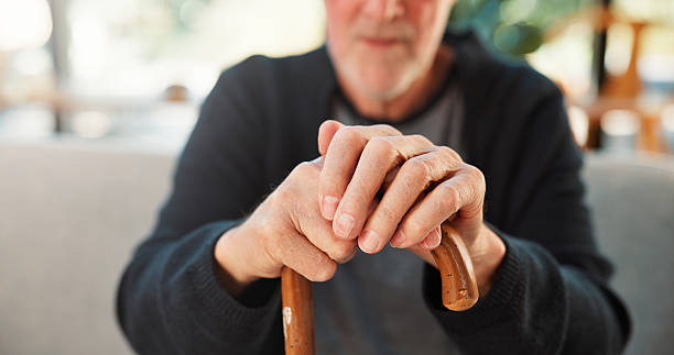 istock Walking stick, home and hands of elderly man on sofa for mobility support, balance and assistance. Retirement, house and person with disability and cane for osteoporosis, arthritis and recovery 2244109665