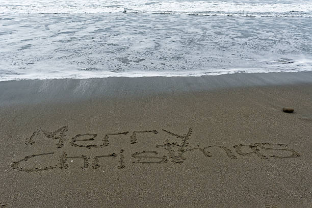 istock Waves lapping at Merry Christmas written in the sand 2244109794