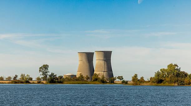 istock Cooling towers by a lake under a blue sky. 2244111417