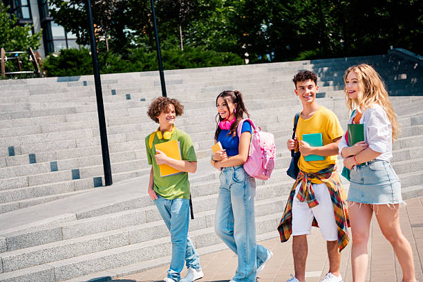 istock Smiling group of diverse students walking together outdoors during a sunny day holding book and backpacks 2244115558