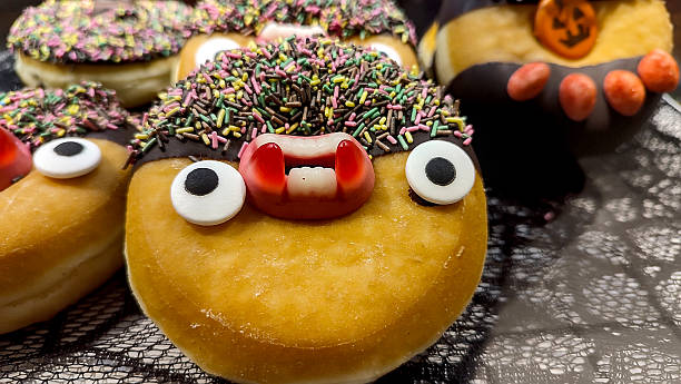 istock Funny Halloween donut decorated with candy eyes, fangs, sprinkles, and chocolate icing. 2244121690