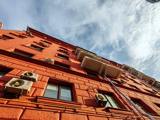 istock A red brick building with multiple air conditioning units mounted on the facade, captured from a dramatic low-angle view. The image emphasizes urban utilities and modern living infrastructure 2244121907