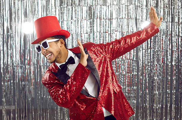istock Funny young black guy in a sequin jacket, top hat and sunglasses dancing at a party 2244123269