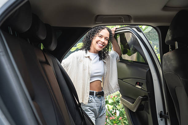istock Happy young woman smiling, getting into rideshare car 2244123648
