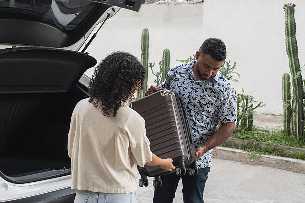 istock Couple packing suitcase into car trunk for road trip 2244126065