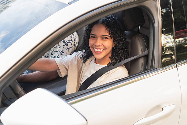 istock Young woman smiling while driving car 2244126166