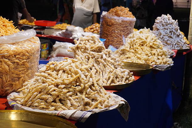 Assorted traditional Indian fried snacks displayed in large piles at night street food market