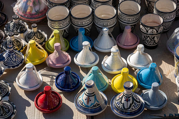 Colorful Moroccan ceramic tagines and cups on display, showcasing traditional craftsmanship, vibrant glazes, and intricate patterns. Authentic North African pottery for cultural and culinary themes.