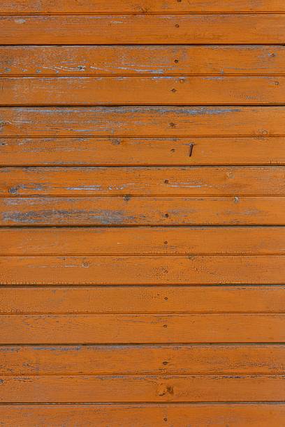 Wooden surface made of horizontal planks painted burnt orange with signs of wear.