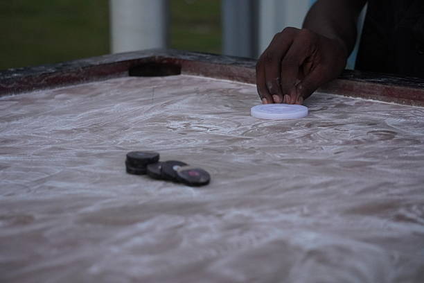 Hand aiming white striker on powdered carrom board during outdoor game