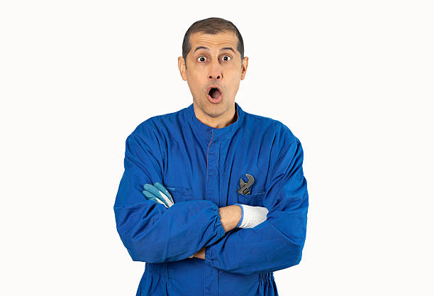 Hispanic man over white background wearing mechanic uniform scared in shock with a surprise face, afraid and excited with fear expression