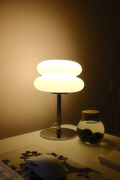 A lamp illuminates a desk with a jar of Marimo moss balls.