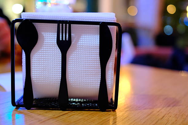 A holder contains white napkins, plus a spoon, fork, and knife.